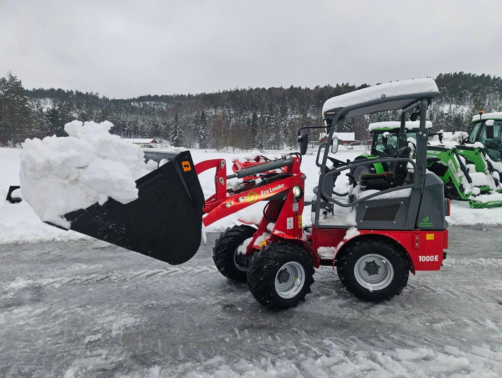 Rød Eco Machines minilaster med skuffe full av snø